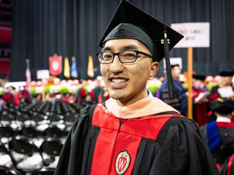 Happy Xiong smiling for a picture in graduation attire