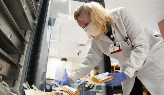 A healthcare worker holding a bag of plasma