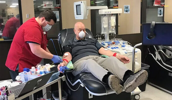 A man donating blood with Red Cross.