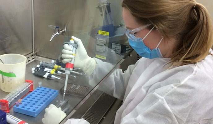 A woman wearing PPE working in a lab