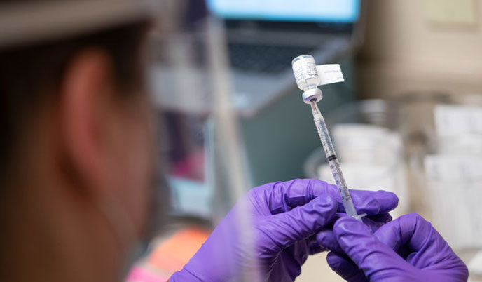 A health professional pulling a vaccine into a syringe