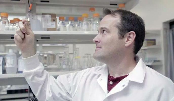 A researcher in a lab inspecting liquid in a syringe