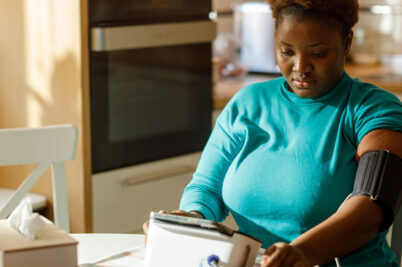 A woman using a blood pressure monitor at home.