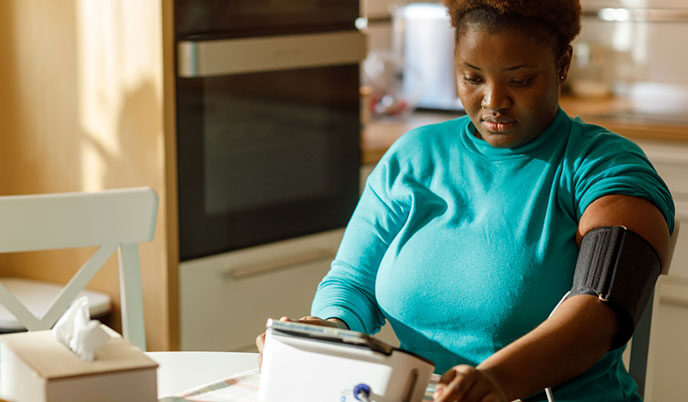 A woman using a blood pressure monitor at home.