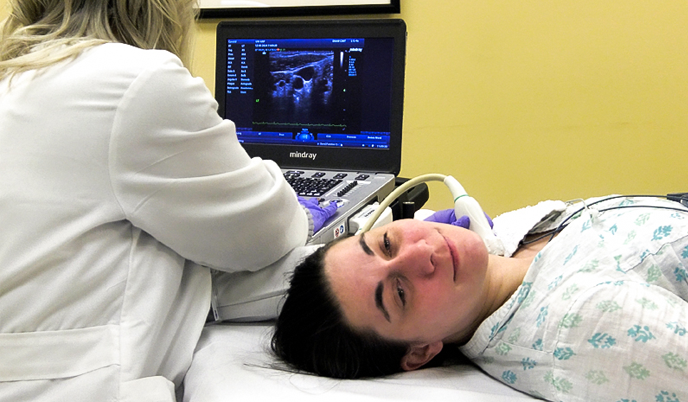 A technician performs and ultrasound on a patient's neck.