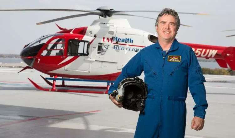 Emergency medicine doctor Michael Abernethy standing in front of a medical helicopter