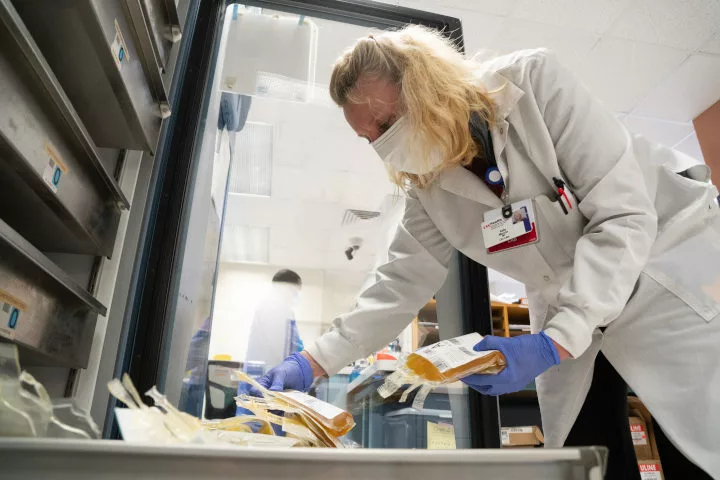 A healthcare worker holding a bag of plasma