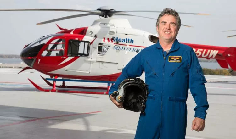 Emergency medicine doctor Michael Abernethy standing in front of a medical helicopter