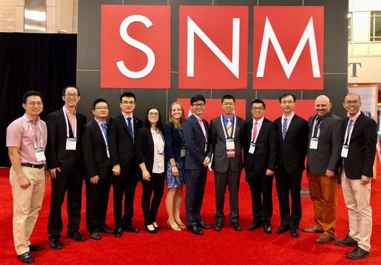 Cai group researchers standing in front of SNMMI meeting signage