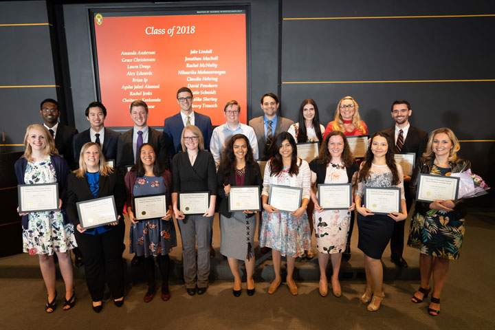 A group of students holding graduation diplomas